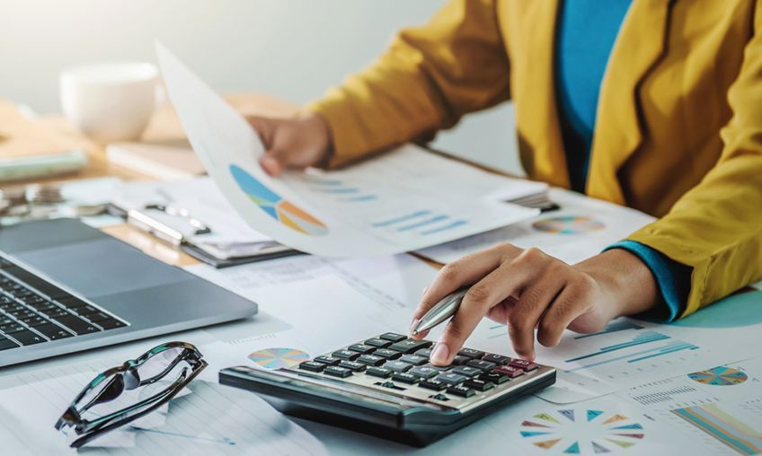 Business paperwork, charts, and calculator for payroll and compliance support.